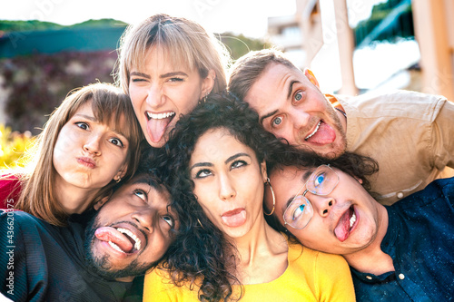 Multiethnic milenial people taking selfie sticking out tongue with happy faces - Funny life style and integration concept with interracial young friends having fun together