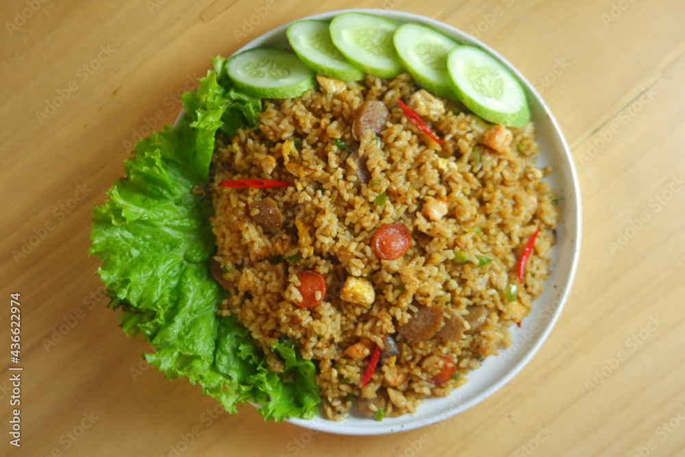 a plate of fried rice served with salad on a wooden table a plate of fried rice served with salad on a wooden table