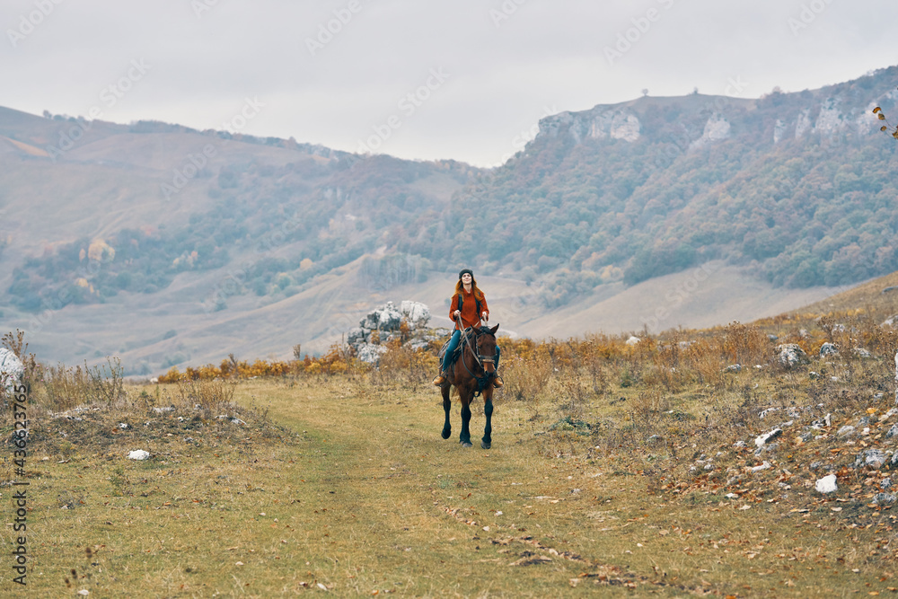 woman hiker in the mountains riding a horse adventure lifestyle
