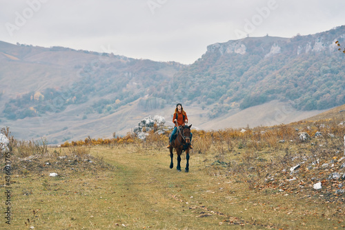 woman hiker in the mountains riding a horse adventure lifestyle