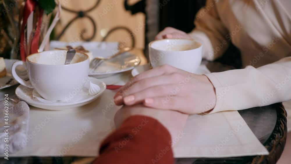 Close up female hand gently stroking male hands while romantic date in restaurant. Female hands touching male hand at restaurant table Close up female hand gently stroking male hands while romantic date in restaurant. Female hands touching male hand at restaurant table