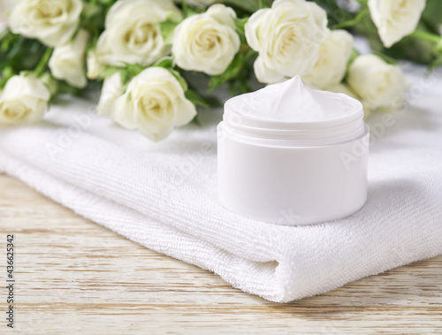 Natural face cream or lotion sensitive skin, organic cosmetic product to moisturize the skin on a background of white roses.