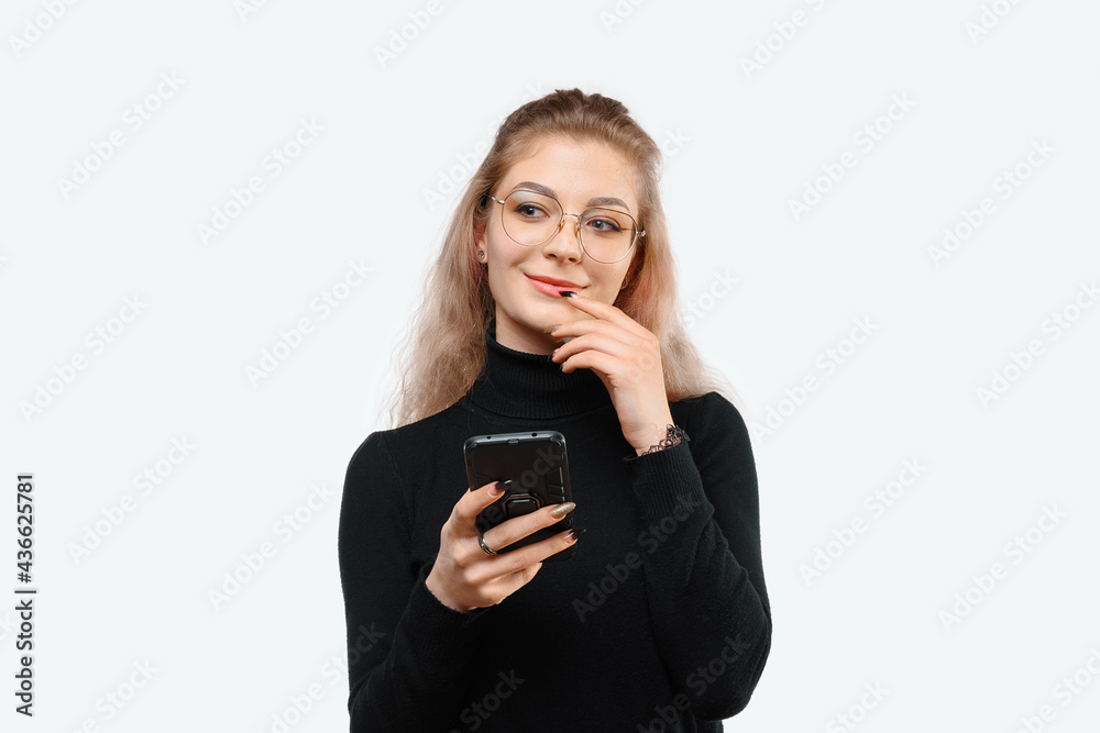 Image of a thoughtful young beautiful woman in casual clothes holding her smart phone. White background Image of a thoughtful young beautiful woman in casual clothes holding her smart phone. White background