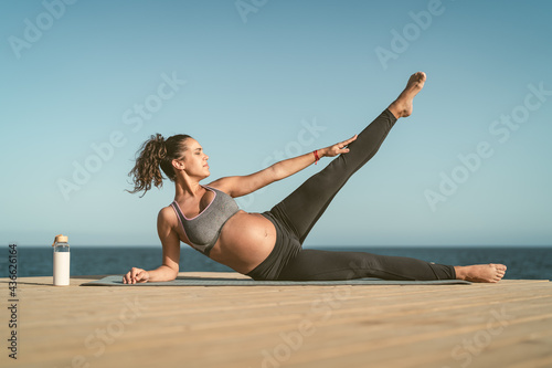 Young pregnant woman doing prenatal pilates exercises session next the sea - Health lifestyle and maternity concept © Alessandro Biascioli