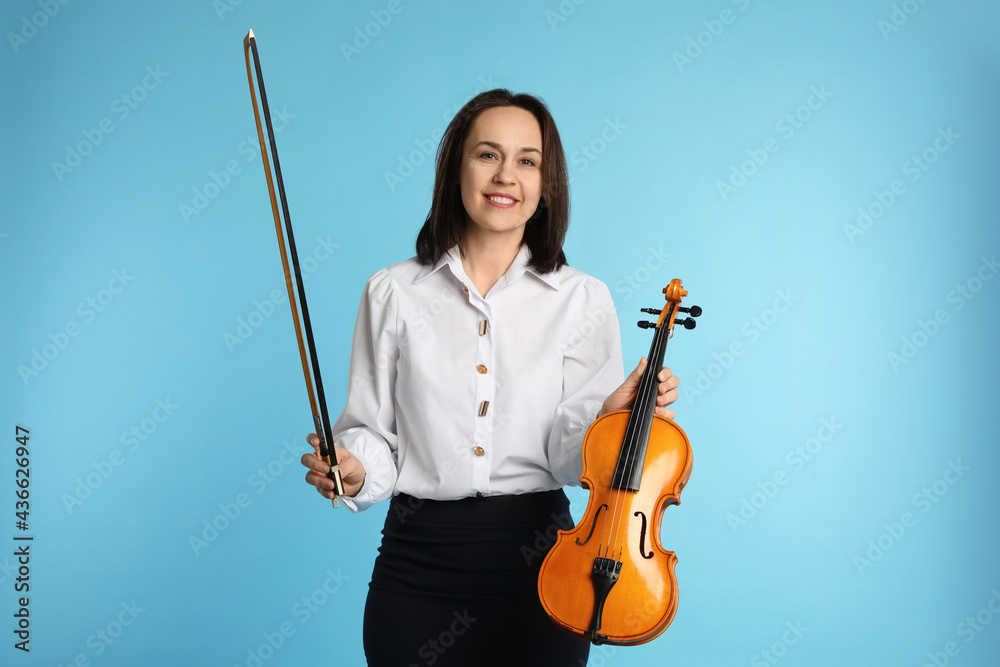 Music teacher with violin and bow on turquoise background Music teacher with violin and bow on turquoise background