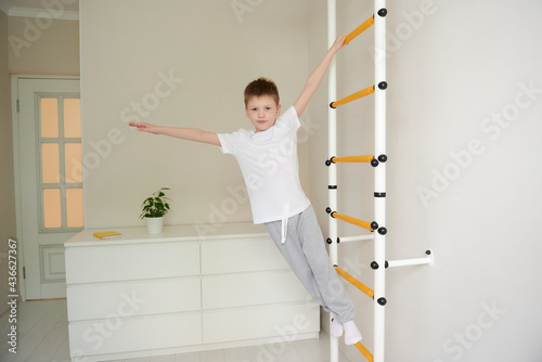 Fototapeta Naklejka Na Ścianę i Meble -  Boy working out with wall bars at home