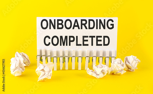 white paper on the yellow background with text ONBOARDING COMLETED photo