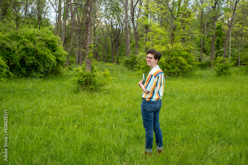 Cheerful person alone outdoors in nature holding a book © Mary Salen