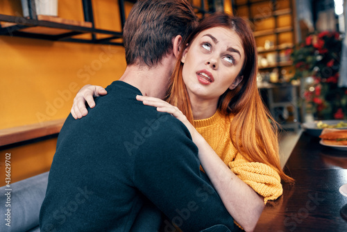 romantic woman hugs a young man in a sweater at a table in a cafe interior a couple in love