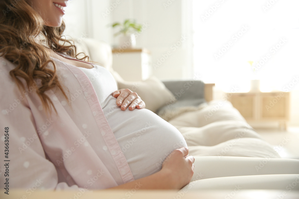 Pregnant woman touching her belly indoors, closeup Pregnant woman touching her belly indoors, closeup