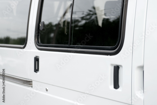 Transparent glass window of the metal door of the minibus.