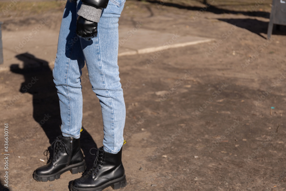 Legs of teenagers in jeans and dark shoes. Spring walk in the park Legs of teenagers in jeans and dark shoes. Spring walk in the park