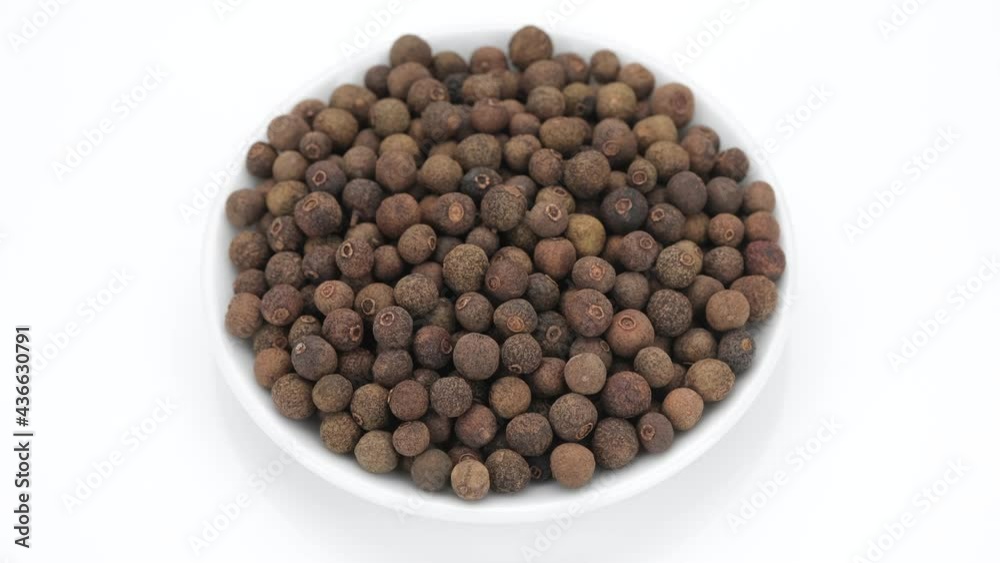 Whole Allspice pepper peas on white background, rotating. 4K UHD video