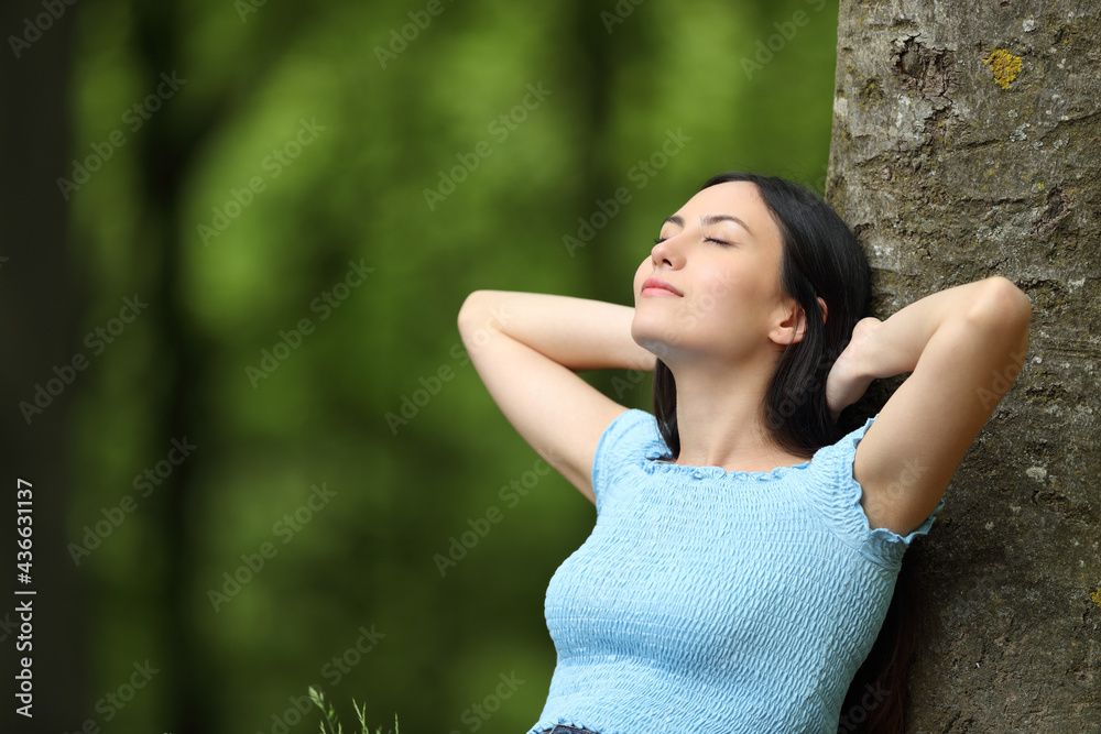 Asian woman resting on a tree in a park