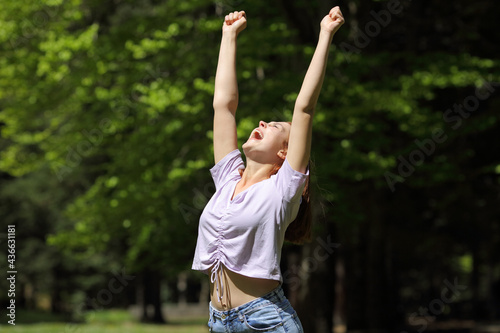 Excited casual woman raising arms in a park