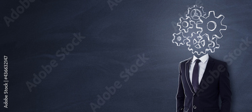 Headless businessman with abstract gear sketch standing on chalkboard background with copy space. Engineering and brainstorm concept. photo