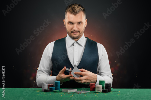 Male dealer at the casino at the table. Casino concept, gambling, poker, chips on the green casino table.