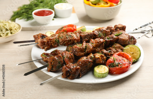 Foto Metal skewers with delicious meat and vegetables served on white wooden table