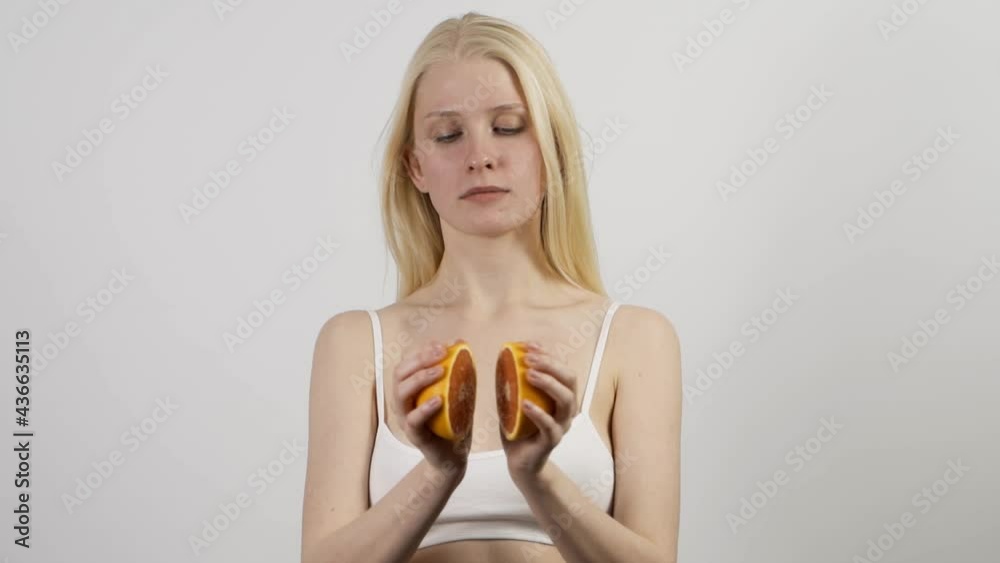 Young slender woman with grapefruit halves on an isolated white background. A beautiful woman separates the halves of a grapefruit and smiles. Slow motion, HD. Young slender woman with grapefruit halves on an isolated white background. A beautiful woman separates the halves of a grapefruit and smiles. Slow motion, HD.
