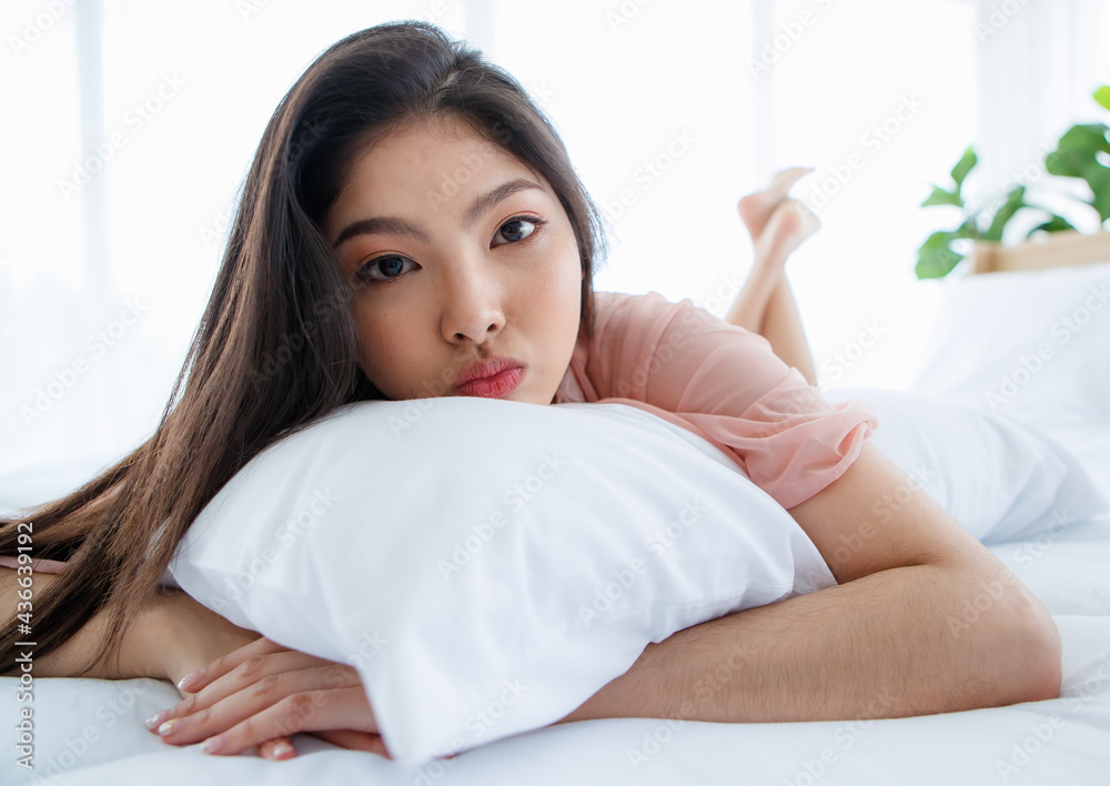 Beautiful young naughty sexy girl with long hair lying down on pillow on white bed end in bright morning and seductively glancing with smile to special one of happy romantic day Beautiful young naughty sexy girl with long hair lying down on pillow on white bed end in bright morning and seductively glancing with smile to special one of happy romantic day