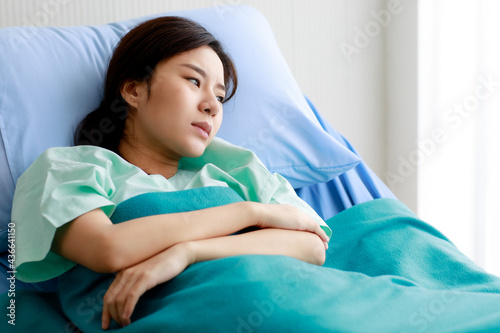 An asian young beautiful female patient getting pain and sick while lying on bed in hospital. Medical Treatment and Health concept.