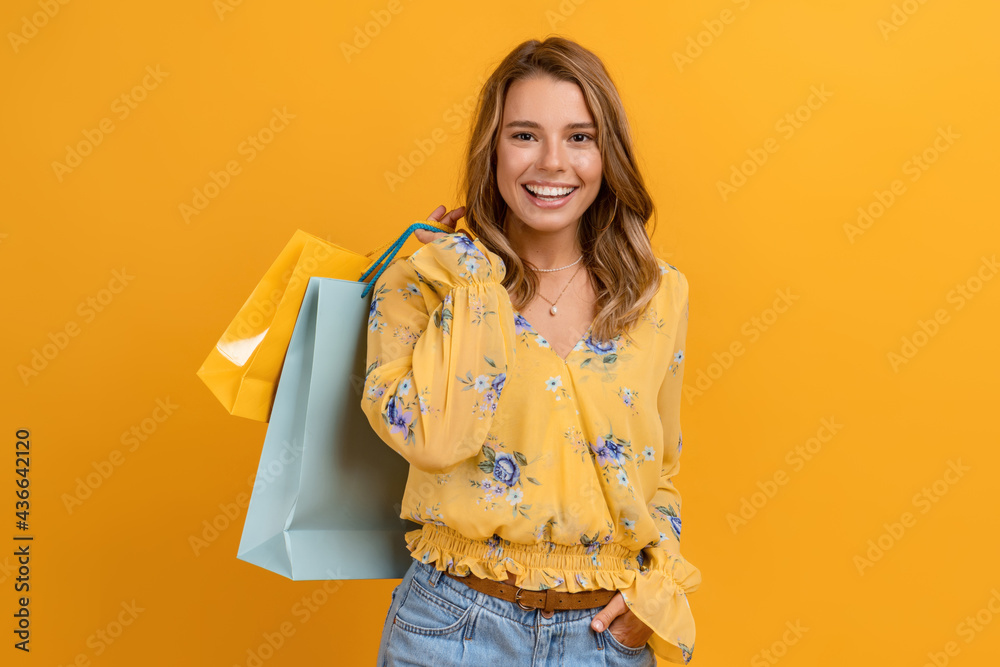 beautiful attractive smiling woman in yellow shirt and jeans holding shopping bags - obrazy, fototapety, plakaty 
