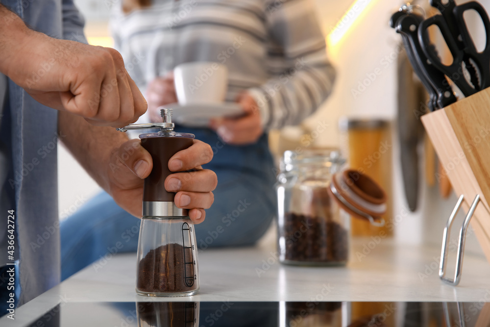Couple together in kitchen. Man using manual coffee grinder, closeup Couple together in kitchen. Man using manual coffee grinder, closeup