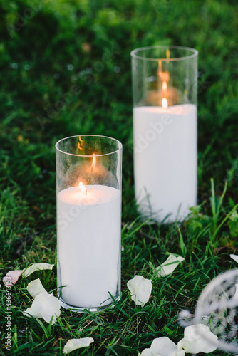 Lighted bulk candles in flasks standing on the grass. Decor for weddings, photo shoots