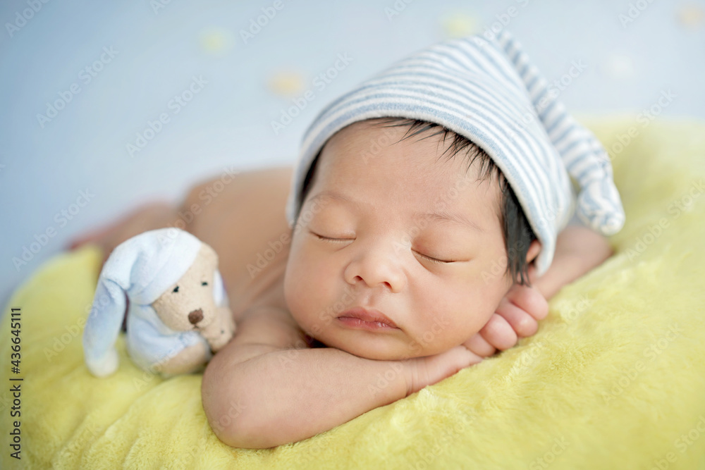 Close up newborn baby wearing a blue and white striped hat. Newborn sleeping on a crescent