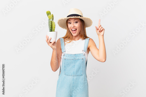 pretty woman feeling like a happy and excited genius after realizing an idea and holding a cactus decorative plant photo