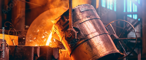 Metal cast process, long banner image. Molten liquid iron pouring from ladle container into mold. photo
