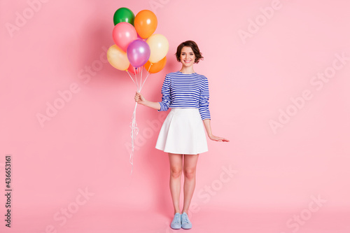 Full size photo of young beautiful smiling cheerful charming girl hold balloons wear mini skirt isolated on pink color background