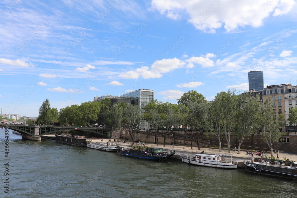 Fototapeta premium Le quai de la Tournelle le long du fleuve Seine, avec la tour Montparnasse en arrière plan, ville de Paris, France