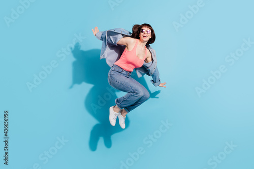 Full length profile photo of crazy young lady jump wear top jeans eyewear isolated on blue color background