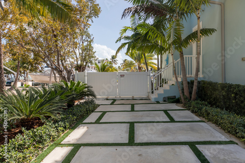 Modern Concrete slabs separated by grass in driveway with white fence. photo