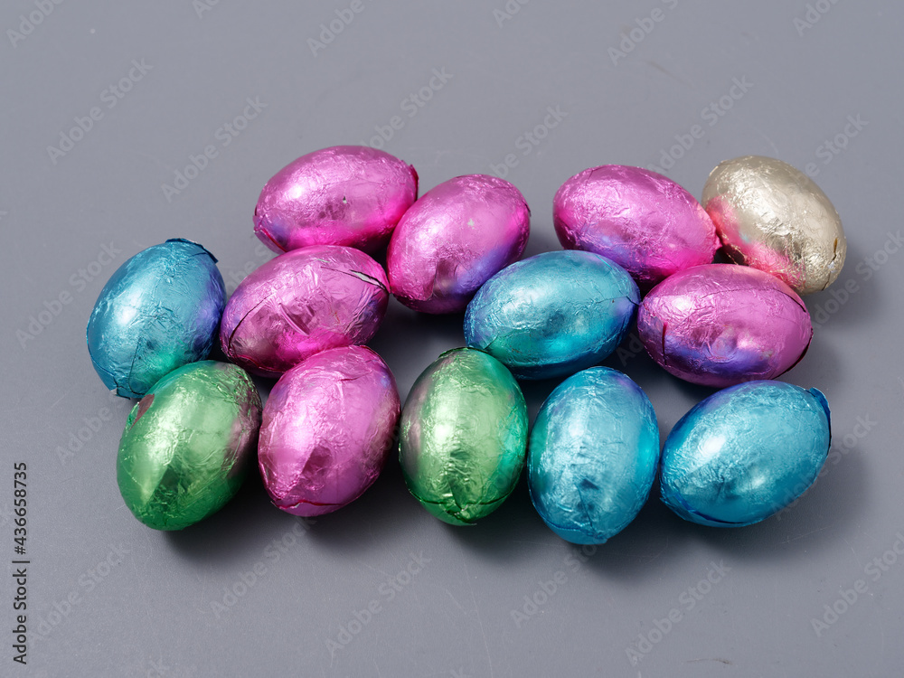 chocolate candies in foil in the form of Easter eggs on a gray background chocolate candies in foil in the form of Easter eggs on a gray background
