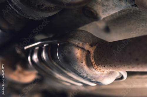 Vehicle underbody exhaust pipe, catalyst, resonator, exhaust system. Old parts require repair and replacement. Car service and maintenance. Standards and technical condition. selective focus