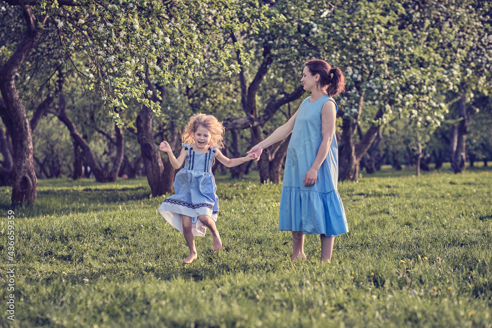 Fototapeta premium nature scene with family outdoor lifestyle. Mother and little daughter playing together in a park. Happy family concept. Happiness and harmony in family life.