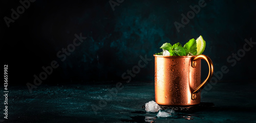 Fotografija Moscow mule alcoholic cocktail in copper mug with lime, ginger beer, vodka and mint