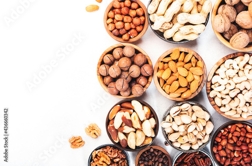 Nuts in bowls set. Cashews, hazelnuts, walnuts, pistachios etc. Healthy food snack mix on white table, top view