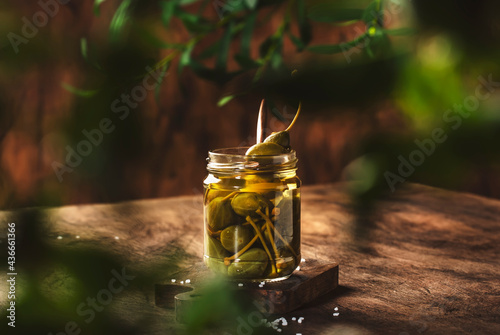 Capers. Marinated or pickled canned capers fruit in glass jar on wooden table, eco style still life photo