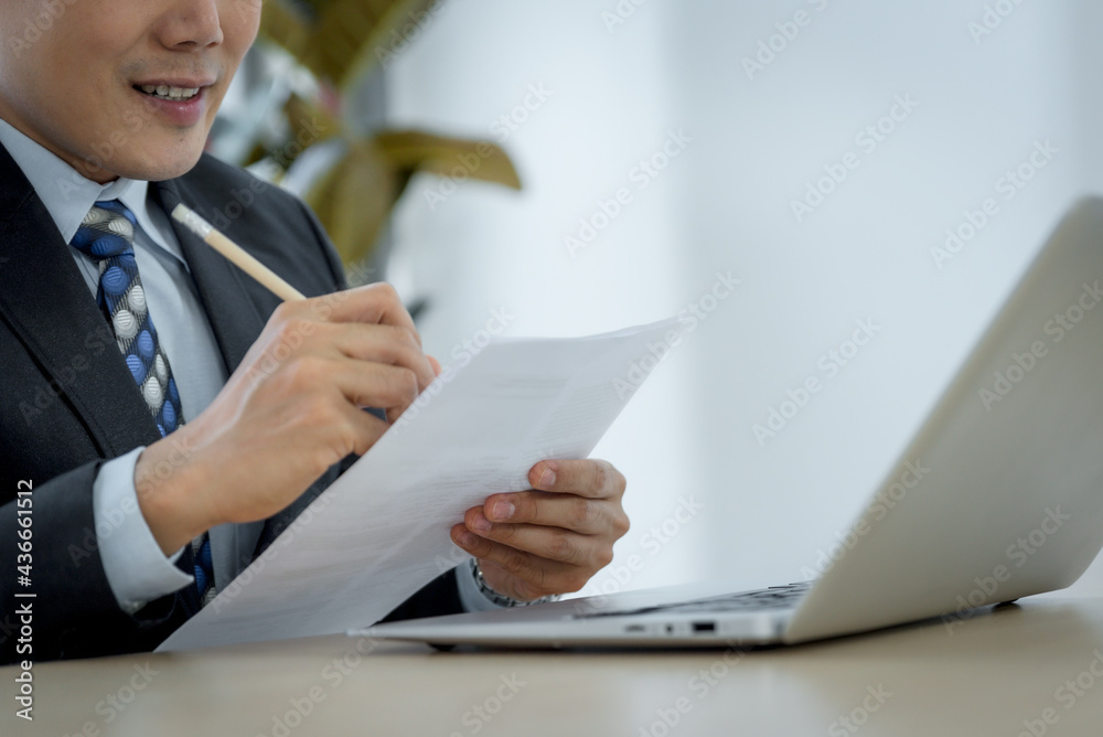 Handsome asina businessman making notes in office. Handsome asina businessman making notes in office.