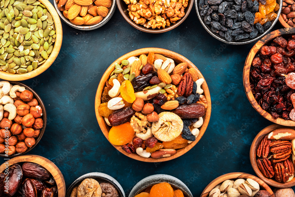 Fototapeta premium Nuts and dried fruits. Dried apricots, figs, raisins, pecans, walnuts, hazelnuts, almonds and other. Blue background, top view
