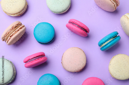Delicious colorful macarons on violet background, flat lay