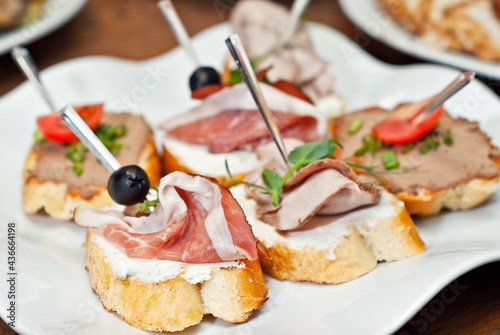 Sandwiches with meat on a white plate. Sandwiches with ham and olives close up.