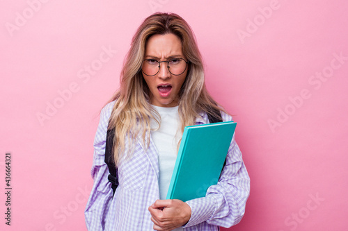 Young student australian woman isolated on pink background screaming very angry and aggressive.
