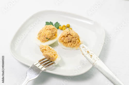stuffed eggs with canned tuna and herbs. cut a piece with a knife and fork
