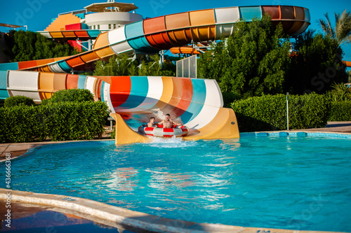 Action shot of father and son at the water park. Have fun together in the aqua park.