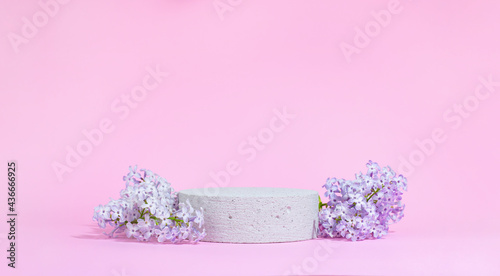 Fotografie, Obraz Concrete cylindrical podium with lilac flowers on a pink background with hard shadows