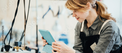 Female local business woman, tailor working in clothes factory, using tablet computer